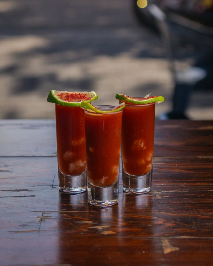 Three shot glasses filled with a bloody drink